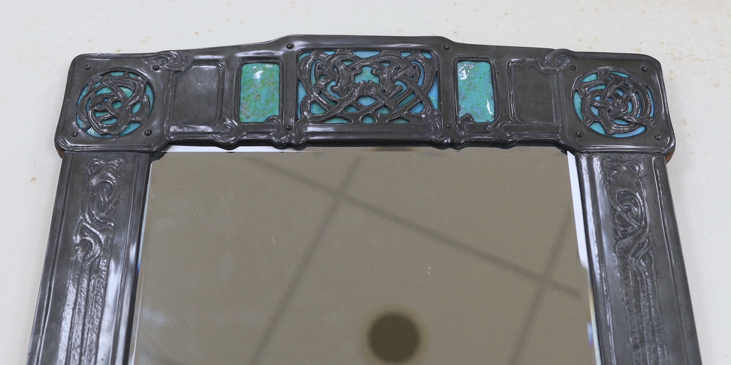 A Miller Brothers Art Nouveau embossed pewter mirror with cabochon turquoise enamel bosses, 48cm high x 39cm wide
